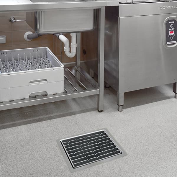 ACO stainless steel floor drain with slotted grate installed in a commercial kitchen floor
