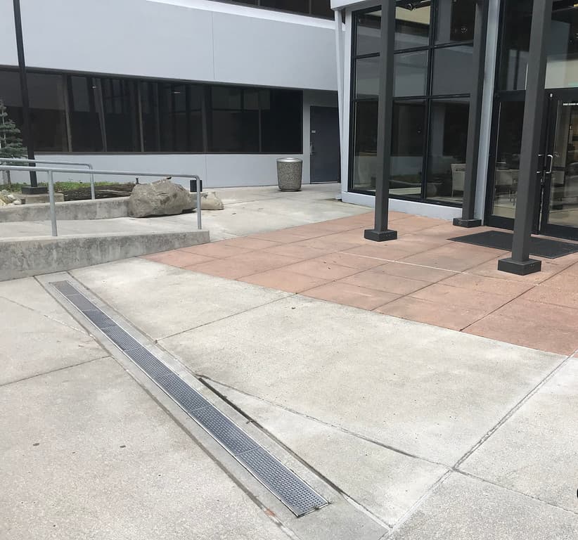 Steel ADA-compliant trench drain grates installed across a commercial plaza entrance